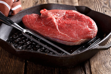 Raw piece of meat for grilling with vegetables in a cast iron pan, close-up, eating out, studio photo