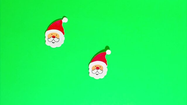 Christmas stop motion animation, many funny santa claus in a red hat, white beard and mustache move on a green chroma key background