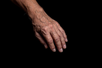 Old man hand on a black background. 
