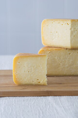 Cutted round partmesan or pecorino cheese head on wooden board on light background. Fresh dairy product, healthy organic food, selective focus, copyspace. Delicious appetizer.