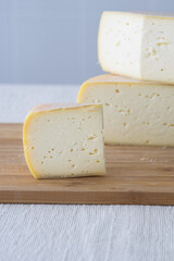 Cutted round partmesan or pecorino cheese head on wooden board on light background. Fresh dairy product, healthy organic food, selective focus, copyspace. Delicious appetizer.