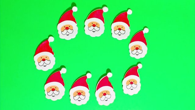 Christmas stop motion animation, many funny santa claus in a red hat, white beard and mustache move on a green chroma key background