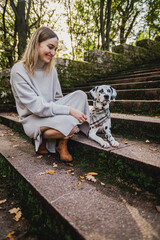 Junge Frau mit jungen Dalmatiner (Junghund / Welpe) während Herbstausflug auf Treppe