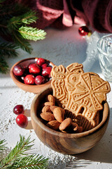 Speculoos or Spekulatius, Christmas biscuits, with cranberry berries, almonds on a table with kitchen towel, fir twigs. Traditional German sweets, cookies for Christmas or Advent, wintertime snacks.