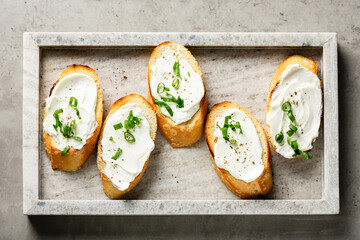 Toasted baguette slices with cream cheese for breakfast.