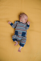 two week old very cute baby in overalls on an orange plaid. High quality photo
