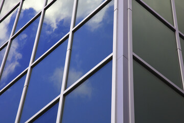 office building glass windows skyscraper corner workplace blue sky clouds graphic reflections