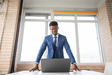 Fototapeta premium portrait of stylish african man in suit at table with laptop 