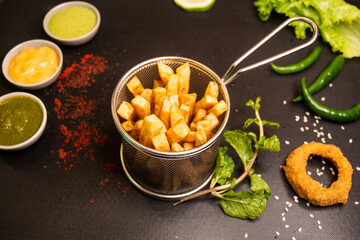 French Fries with onion ring and sauces served in a fryer isolated on table top view of fastfood