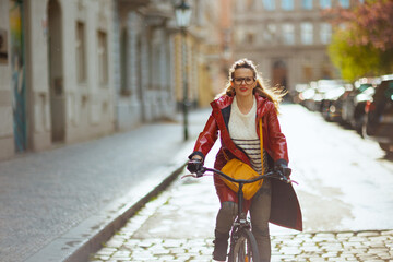 stylish woman outdoors on city street riding bicycle