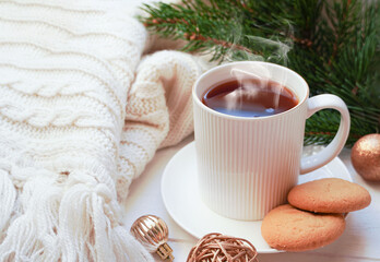    Winter, Christmas, New Year decorations composition, concept, background. White Mug, cup of tea, coffee, steam, spruce branches, knitted plaid. Christmas mood morning. Christmas greeting card.