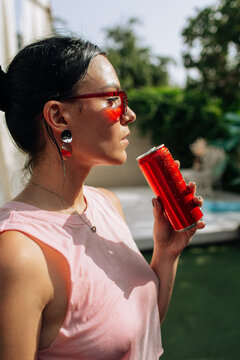 A girl on an orange background with a red tin can in her hands. Cheerful girl, advertising shooting. High quality photo
