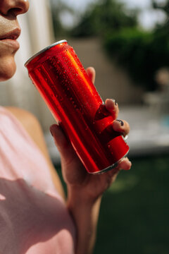 A girl on an orange background with a red tin can in her hands. Cheerful girl, advertising shooting. High quality photo
