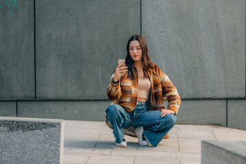 girl in autumn clothes on the street with mobile phone, urban scene