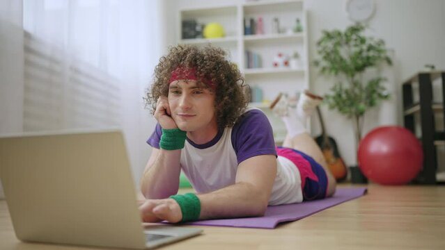 Cute man in sportswear surfing web instead of doing exercises, procrastination