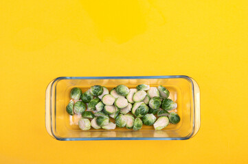 Sliced Brussels sprouts in a glass baking dish on a yellow background