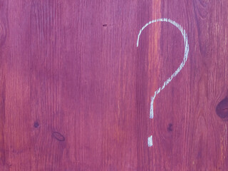 Question mark handwritten in white chalk on purple wooden surface