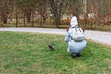 Woman feeding squirrel at park, in winter.