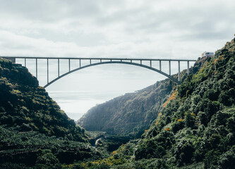 Bridge in the middle of savage and green forest and mountains. Sea in the background