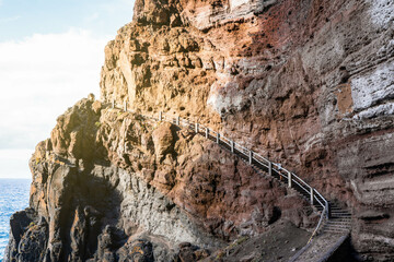 Woman standing on the stairs in heavy and savage craggy mountain near the sea