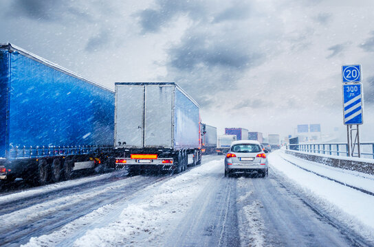 Lkws Transporter auf deutscher Autobahn im Winter mit Schnee und Schneematsch im Stau