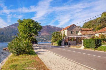 Fototapeta na wymiar Autumn Balkan road trip. View of Adriatic Highway (Jadranska magistrala) running along coast of Kotor Bay. Montenegro, Donja Lastva village