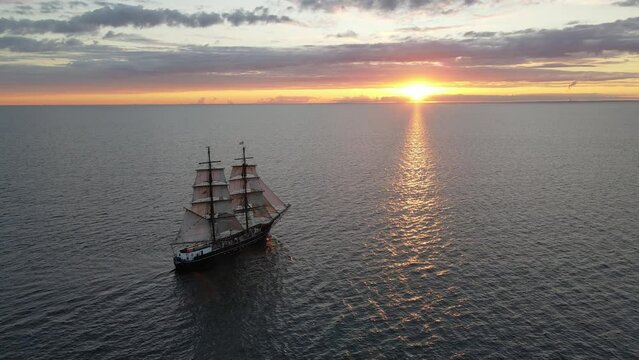 Aerial shot of an old sailing ship into the sunset