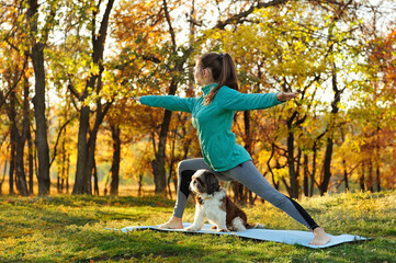 Sportive young woman practicing warrior yoga pose in autumn forest