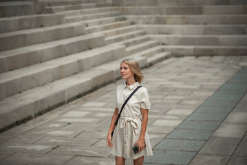 stylish beautiful woman 42 years old who looks younger than her age on the street in a white dress