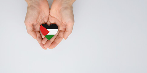 The national flag of Palestine in the shape of a heart in the hands. Flat lay, copy space.