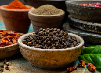 Indian spices collection, dried black peppercorns and another spices in clay bowls