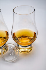 Tulip-shaped tasting glasses with dram of Scotch single malt or blended whisky on white background