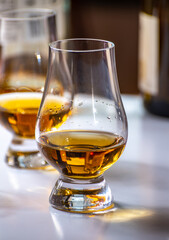 Tasting of whiskey, tulip-shaped tasting glasses with dram of Scotch single malt or blended whisky on white table