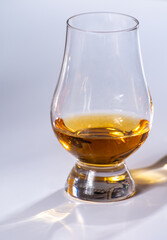 Tulip-shaped tasting glass with dram of Scotch single malt or blended whisky on white background