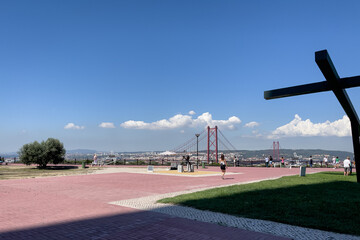 People visiting the Sanctuary of Christ the King in Lisbon with a view over April 25th bridge