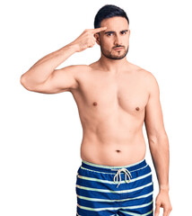 Fototapeta premium Young handsome man wearing swimwear pointing unhappy to pimple on forehead, ugly infection of blackhead. acne and skin problem