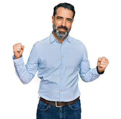 Middle aged man with beard wearing business shirt very happy and excited doing winner gesture with arms raised, smiling and screaming for success. celebration concept.