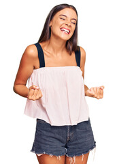 Young hispanic woman wearing casual clothes very happy and excited doing winner gesture with arms raised, smiling and screaming for success. celebration concept.