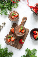 Festive homemade delicious chocolate mousse or panna cotta with berries on a white stone background. Vertical