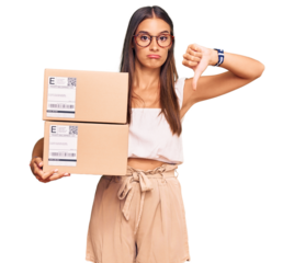 Young hispanic woman holding delivery package with angry face, negative sign showing dislike with thumbs down, rejection concept