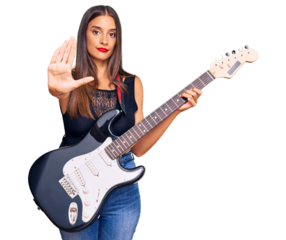 Young hispanic woman playing electric guitar with open hand doing stop sign with serious and confident expression, defense gesture