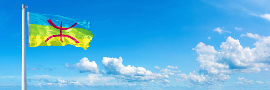 Berbers Amazighs flag waving on a blue sky in beautiful clouds - Horizontal banner
