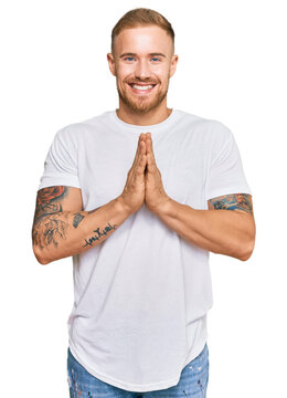 Young irish man wearing casual clothes praying with hands together asking for forgiveness smiling confident.