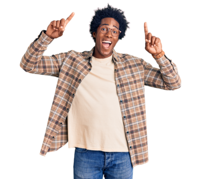 Handsome african american man with afro hair wearing casual clothes and glasses smiling amazed and surprised and pointing up with fingers and raised arms.