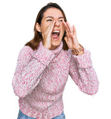 Young caucasian girl wearing wool winter sweater shouting angry out loud with hands over mouth