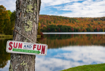 Perfectly calm Silver Lake in Barnard Vermont with humorous Jump in the lake sign on tree