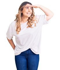 Fototapeta premium Young caucasian woman wearing casual clothes very happy and smiling looking far away with hand over head. searching concept.