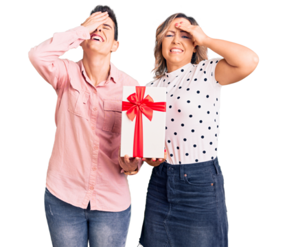 Couple of women holding gift stressed and frustrated with hand on head, surprised and angry face