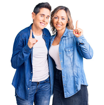 Couple of women wearing casual clothes pointing finger up with successful idea. exited and happy. number one.