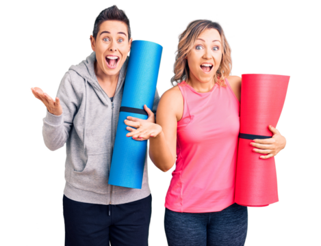 Couple of women holding yoga mat celebrating victory with happy smile and winner expression with raised hands